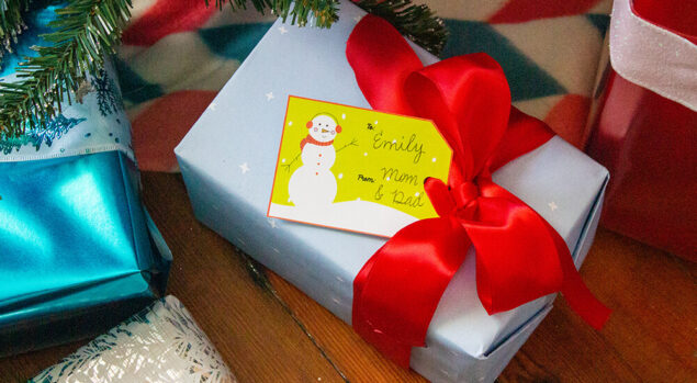 A snow man gift tag on a present under the tree